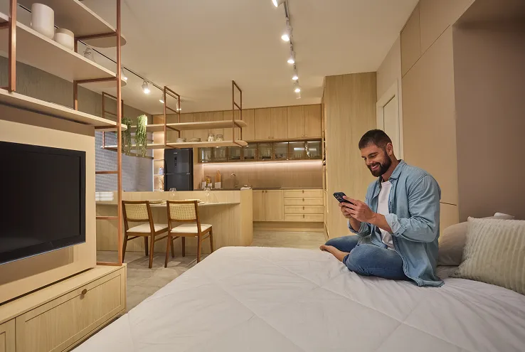 Homem sentado na cama usando o celular em quarto planejado