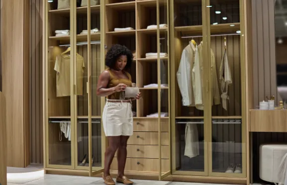 Mulher em frente a closet planejado com portas de vidro